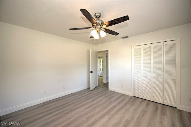 unfurnished bedroom with ceiling fan, a closet, a textured ceiling, and light hardwood / wood-style flooring