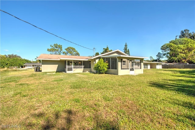 rear view of property featuring a lawn and a sunroom