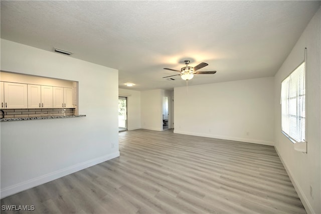 unfurnished living room with ceiling fan, light hardwood / wood-style flooring, and a textured ceiling