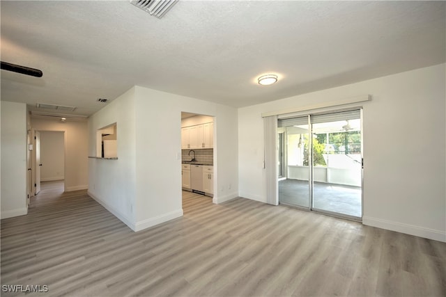 spare room featuring sink, a textured ceiling, and light hardwood / wood-style flooring