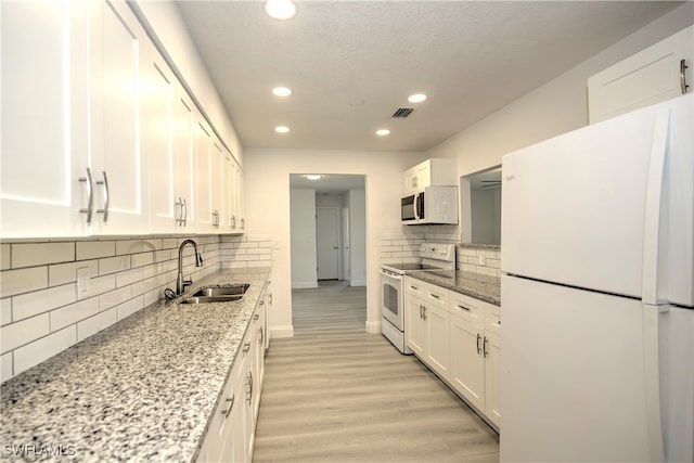 kitchen featuring white cabinetry, sink, light stone counters, white appliances, and light wood-type flooring