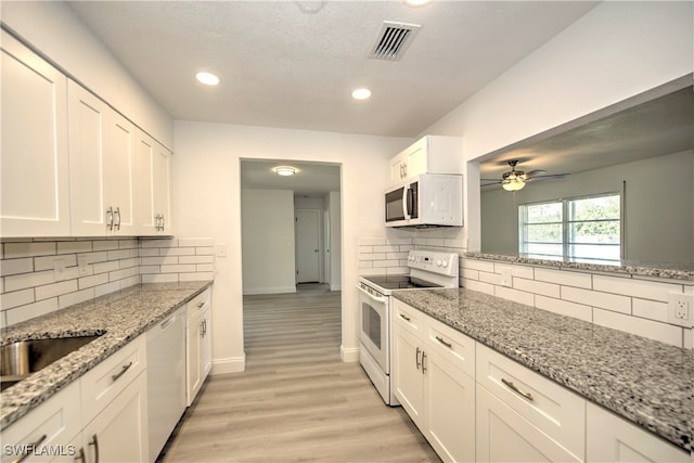 kitchen featuring white cabinets, light stone countertops, white appliances, and backsplash