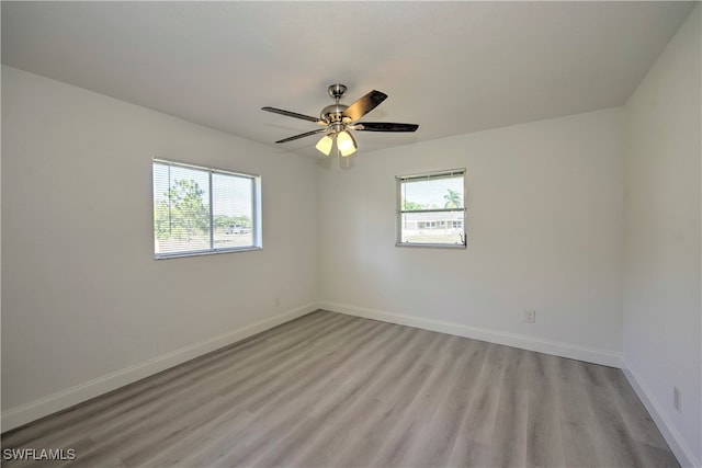 empty room with ceiling fan, plenty of natural light, and light hardwood / wood-style floors