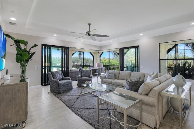 living room featuring a raised ceiling and ceiling fan