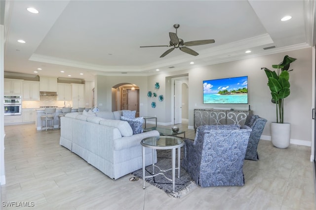 living room with a tray ceiling, ceiling fan, and ornamental molding