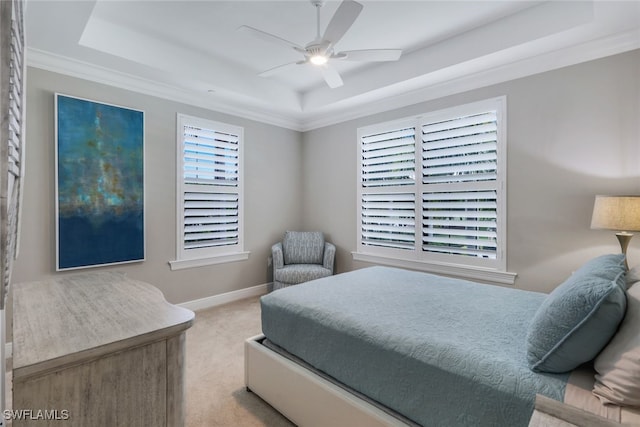 carpeted bedroom with a tray ceiling, ceiling fan, and ornamental molding