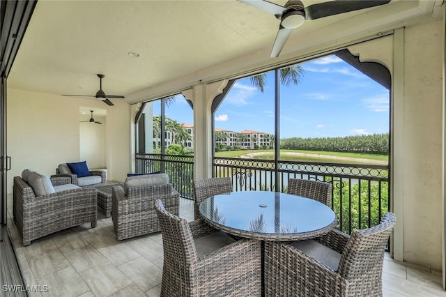 sunroom featuring ceiling fan and a water view