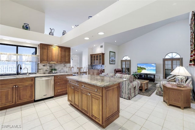 kitchen featuring dishwasher, sink, light stone counters, decorative backsplash, and a kitchen island