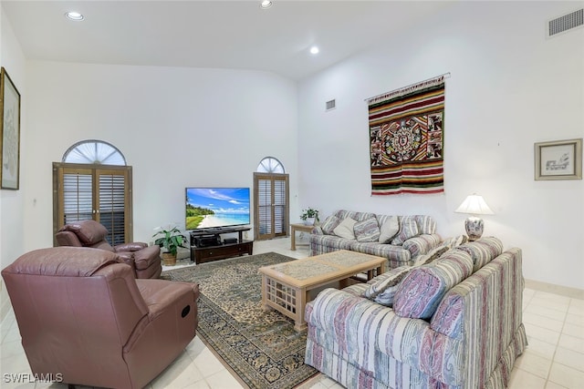 living room with a towering ceiling and light tile patterned floors