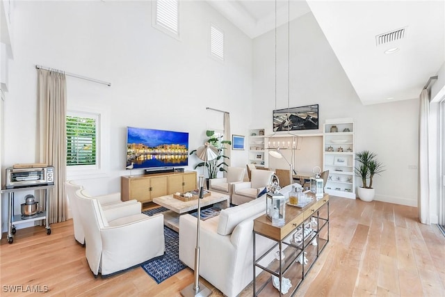 living room with a towering ceiling and light hardwood / wood-style floors