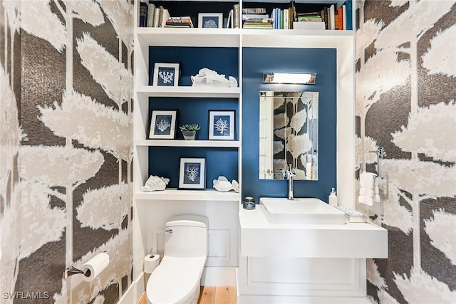 bathroom featuring hardwood / wood-style flooring, toilet, built in features, and sink