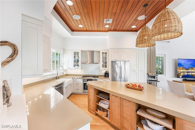 kitchen with a wealth of natural light, wooden ceiling, wall chimney range hood, decorative light fixtures, and appliances with stainless steel finishes