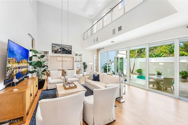 living room with light wood-type flooring and a towering ceiling