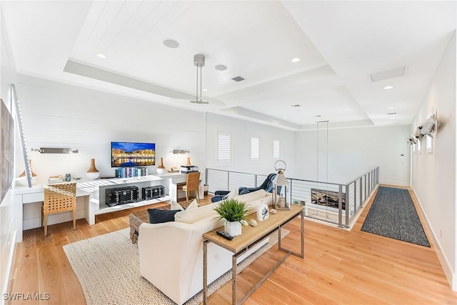 living room with light hardwood / wood-style floors and a raised ceiling