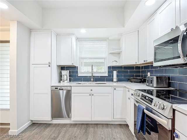 kitchen featuring sink, appliances with stainless steel finishes, tasteful backsplash, light hardwood / wood-style floors, and white cabinetry