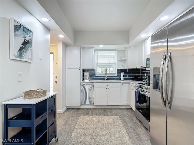 kitchen with white cabinets, light wood-type flooring, stainless steel appliances, and sink