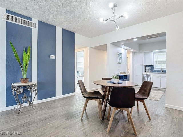 dining area featuring a chandelier, a textured ceiling, and light hardwood / wood-style flooring