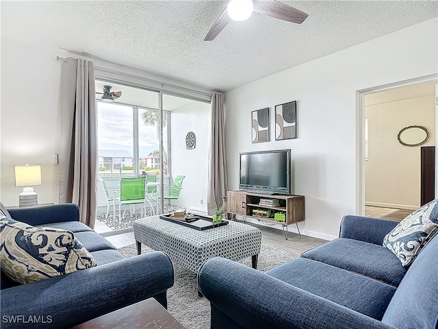 living room with ceiling fan, light hardwood / wood-style floors, and a textured ceiling