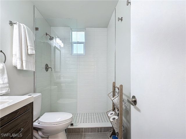 bathroom with tile patterned floors, vanity, toilet, and a tile shower