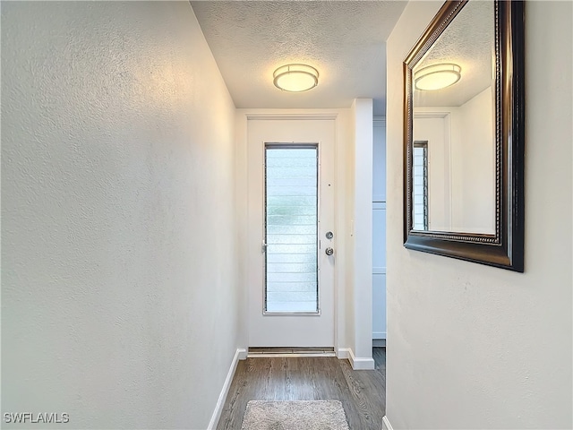 doorway to outside with dark hardwood / wood-style flooring and a textured ceiling