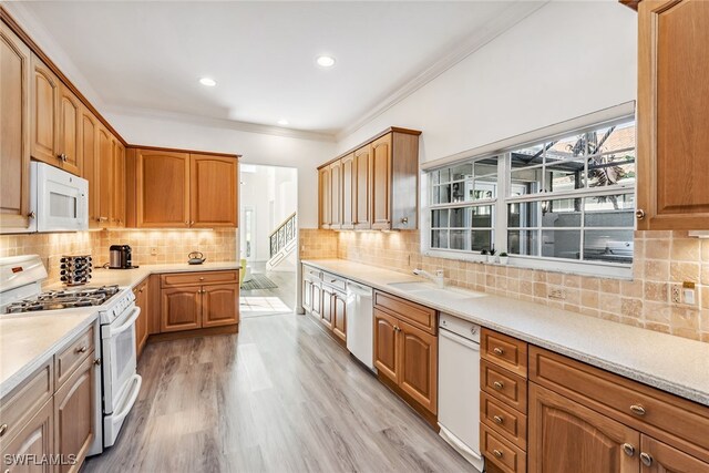 kitchen with white appliances, sink, crown molding, decorative backsplash, and light hardwood / wood-style floors