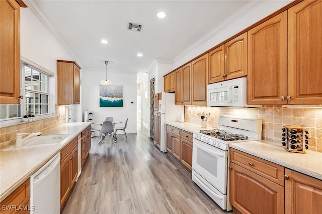 kitchen featuring light wood-type flooring, white appliances, crown molding, sink, and hanging light fixtures