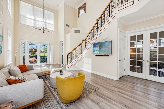 living room with wood-type flooring, french doors, ornamental molding, and a high ceiling