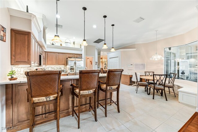 kitchen with pendant lighting, backsplash, stainless steel fridge with ice dispenser, and crown molding