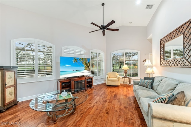 living room with hardwood / wood-style floors, high vaulted ceiling, and ceiling fan