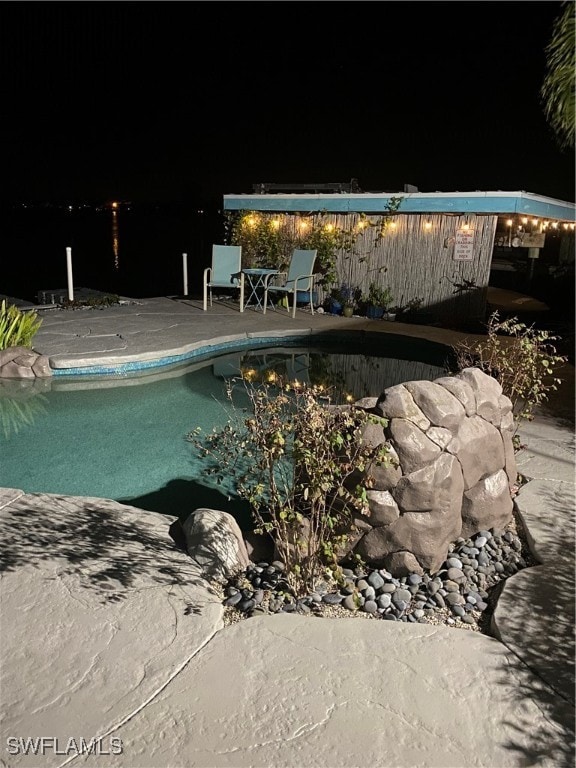 pool at twilight with a patio area