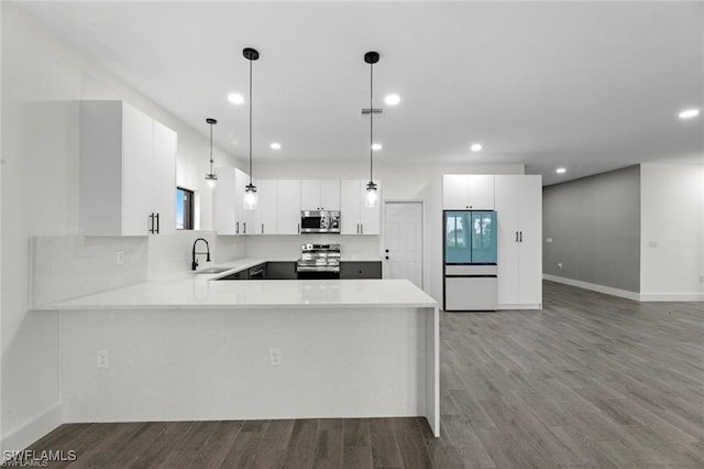 kitchen featuring white cabinets, sink, hanging light fixtures, kitchen peninsula, and stainless steel appliances