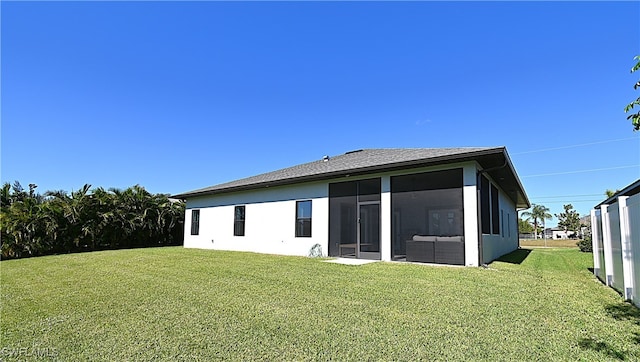 rear view of property with a lawn and a sunroom