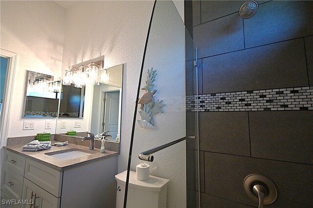 bathroom with vanity, toilet, and tiled shower