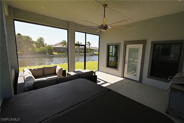 sunroom / solarium with ceiling fan and a water view