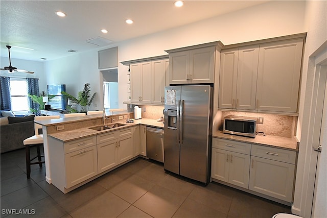 kitchen featuring kitchen peninsula, appliances with stainless steel finishes, backsplash, a breakfast bar, and sink