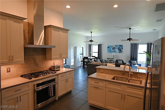 kitchen featuring cream cabinets, sink, wall chimney exhaust hood, dark tile patterned floors, and appliances with stainless steel finishes