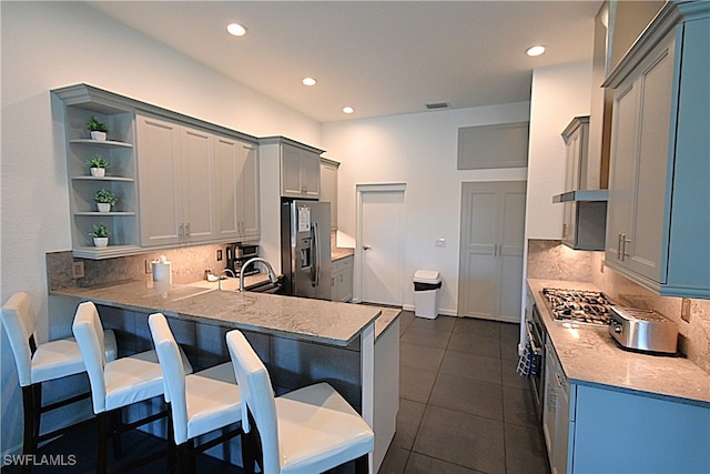 kitchen featuring a kitchen bar, kitchen peninsula, stainless steel appliances, and tasteful backsplash