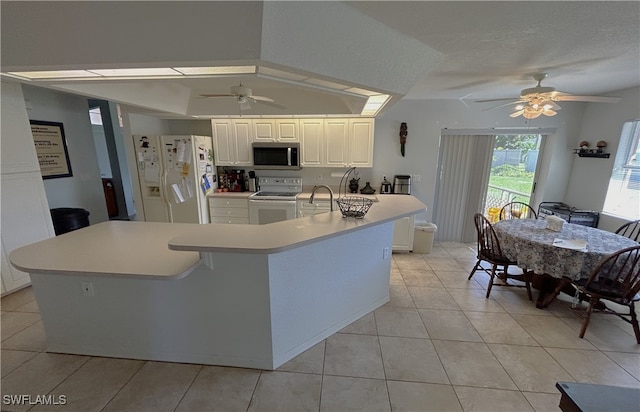 kitchen featuring white appliances, white cabinetry, a kitchen island, and vaulted ceiling