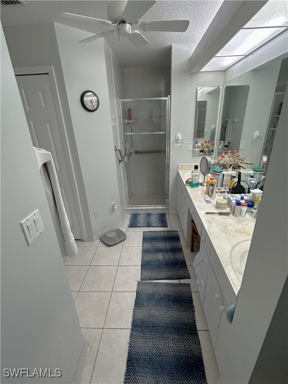 bathroom featuring a shower with door, vanity, a textured ceiling, and tile patterned flooring