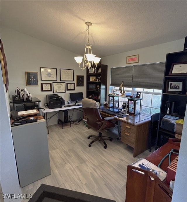 home office featuring lofted ceiling, light wood-type flooring, a textured ceiling, and a notable chandelier