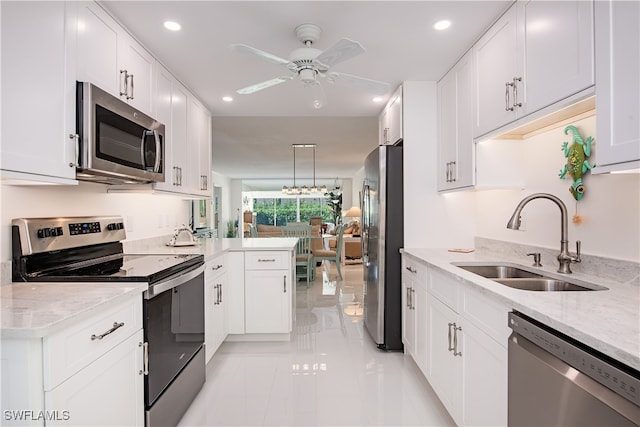 kitchen with sink, stainless steel appliances, light stone counters, decorative light fixtures, and white cabinets