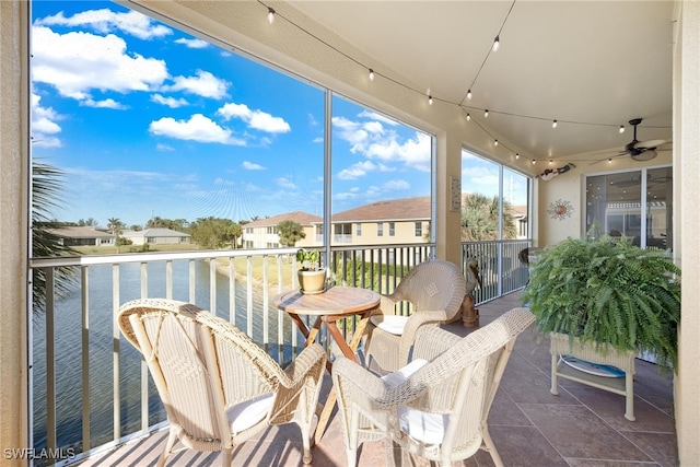 sunroom / solarium featuring ceiling fan and a water view