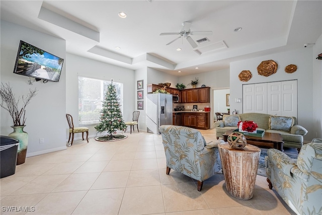 living room featuring ceiling fan, light tile patterned floors, and a tray ceiling