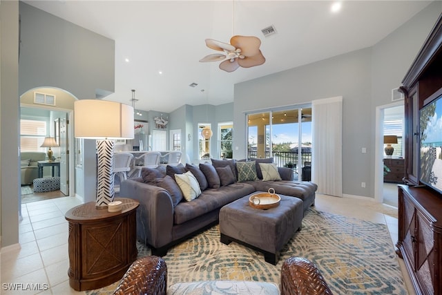 tiled living room with ceiling fan and high vaulted ceiling