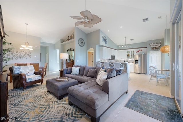 tiled living room featuring high vaulted ceiling and ceiling fan with notable chandelier