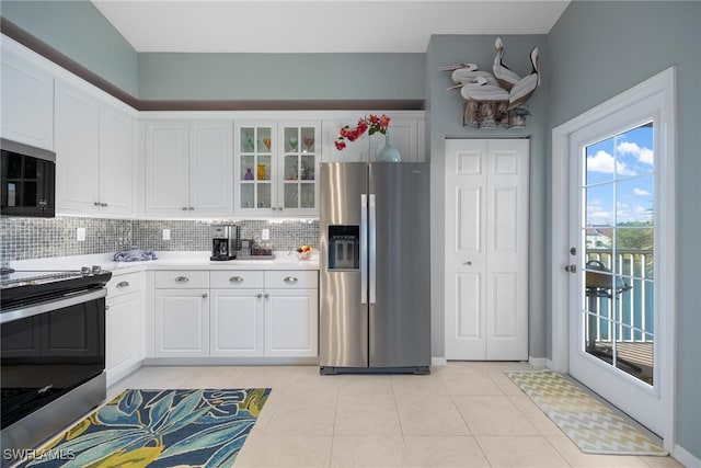 kitchen featuring white cabinets, appliances with stainless steel finishes, decorative backsplash, and light tile patterned flooring