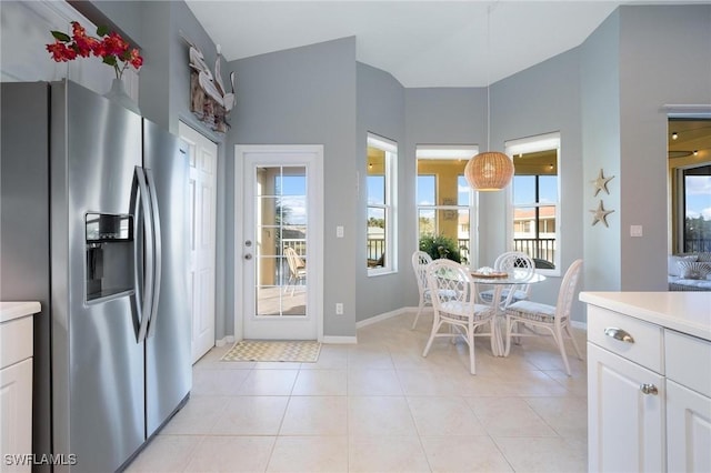 interior space featuring light tile patterned flooring, decorative light fixtures, white cabinets, and stainless steel fridge with ice dispenser