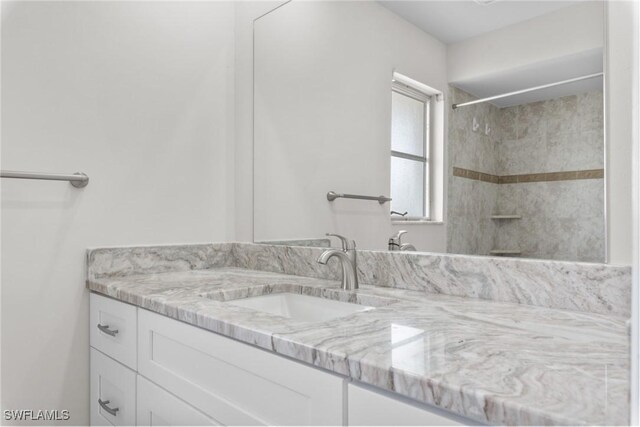 bathroom featuring a tile shower and vanity