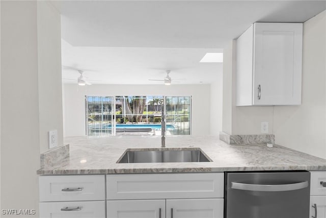 kitchen featuring light stone counters, white cabinetry, stainless steel dishwasher, and ceiling fan