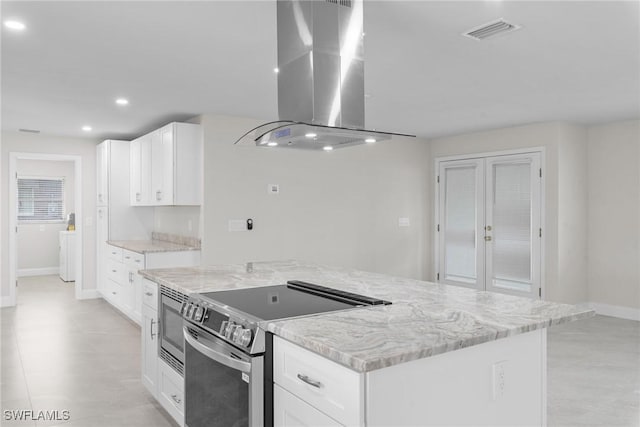 kitchen with appliances with stainless steel finishes, island range hood, white cabinets, and a kitchen island